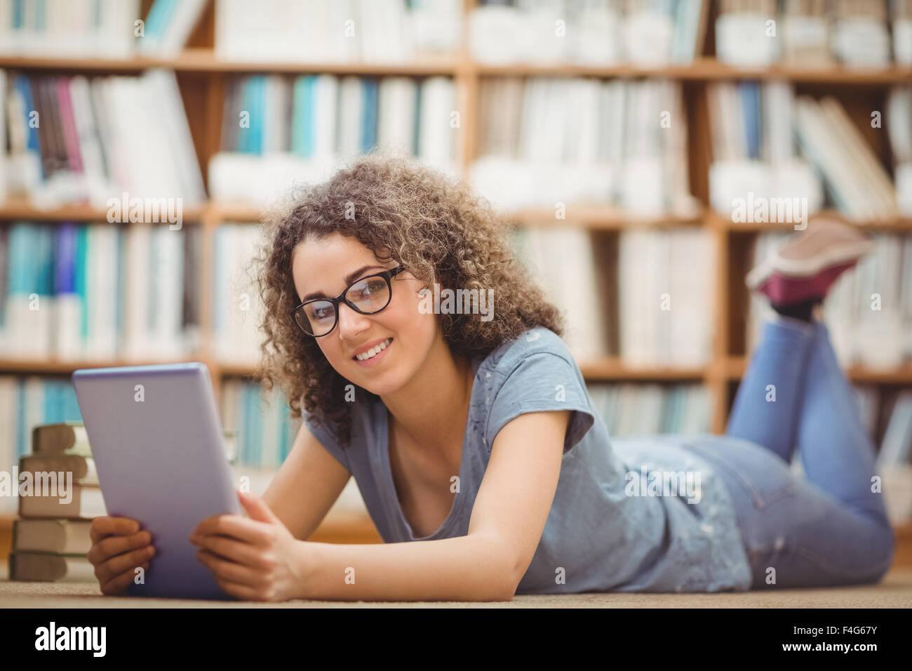 Hübsche Studentin in der Bibliothek mit tablet Stockfoto