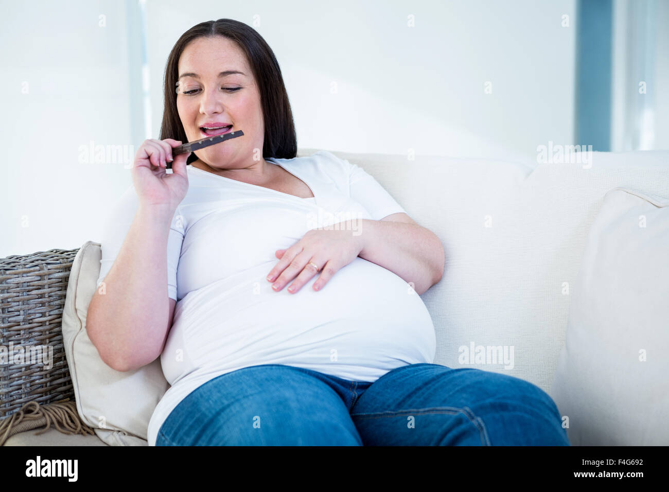 Lächelnde schwangere Frau Schokolade essen Stockfoto