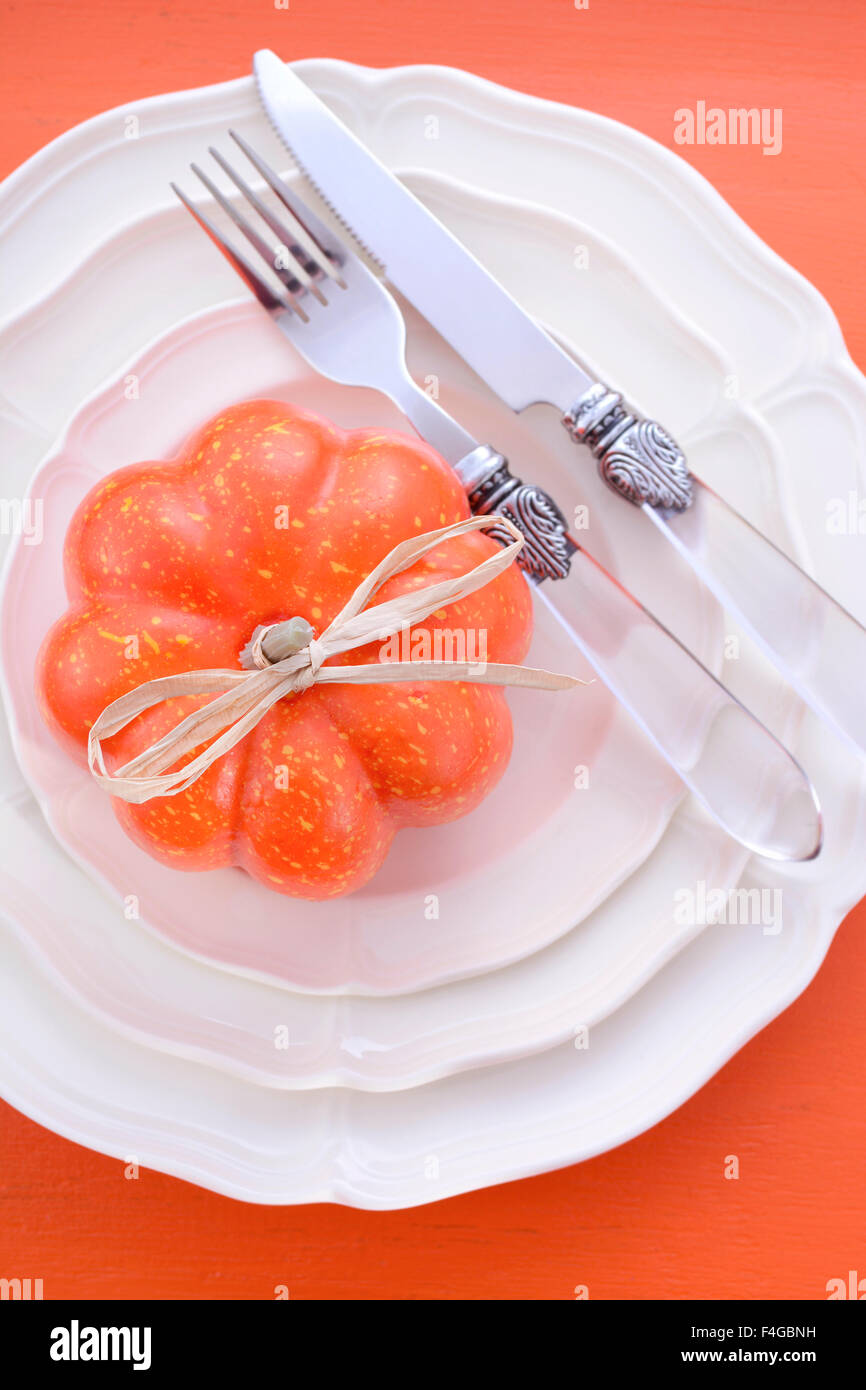 Halloween oder Thanksgiving formalen Ort Tischdekoration mit Kürbis und Vintage Besteck und feines Porzellanteller auf rustikalen orange Stockfoto