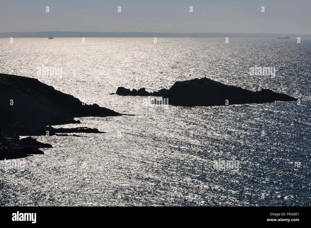 Blick von den Klippen an der Caerfai Bucht, Pembrokeshire der Sonne glitzerte das Meer mit den dunklen Formen der Inseln. Stockfoto