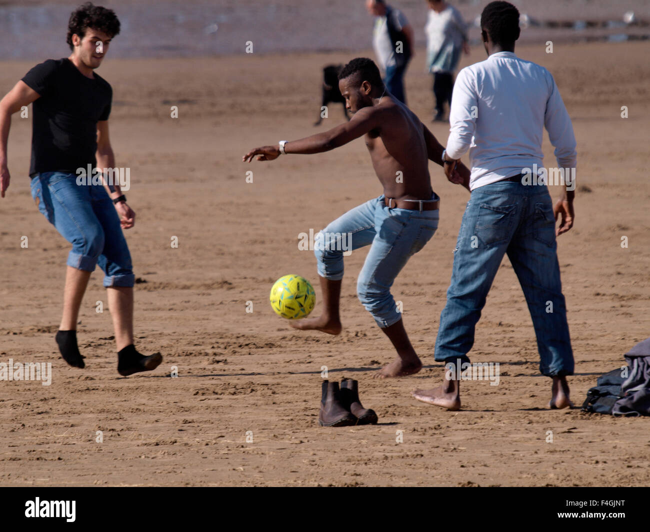 Multi-ethnischen Gruppe junger Männer, die Fußball spielen auf dem Strand, Weston-super-Mare, Somerset, Großbritannien Stockfoto