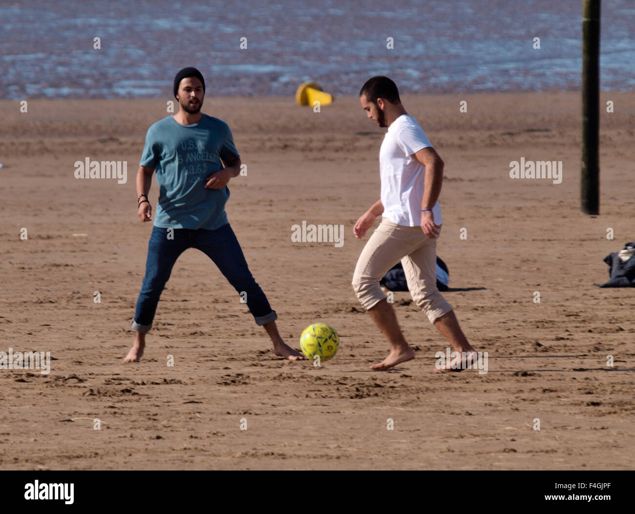 Multi-ethnischen Gruppe junger Männer, die Fußball spielen auf dem Strand, Weston-super-Mare, Somerset, Großbritannien Stockfoto