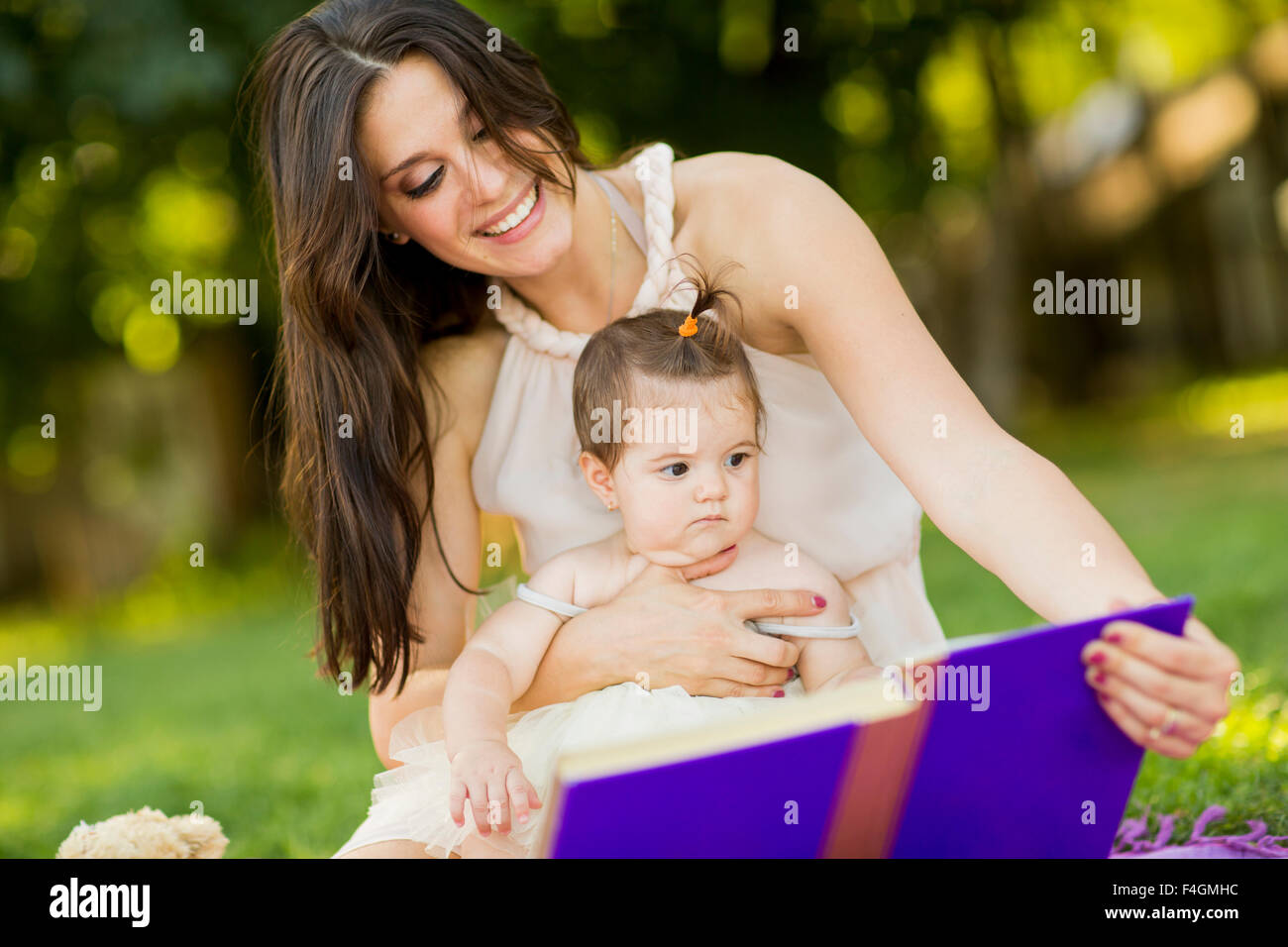 Mutter und Baby Mädchen mit Buch im park Stockfoto