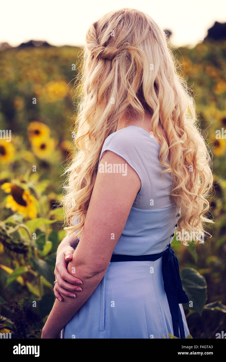 Schöne blonde Frau in einem Sonnenblumenfeld Stockfoto