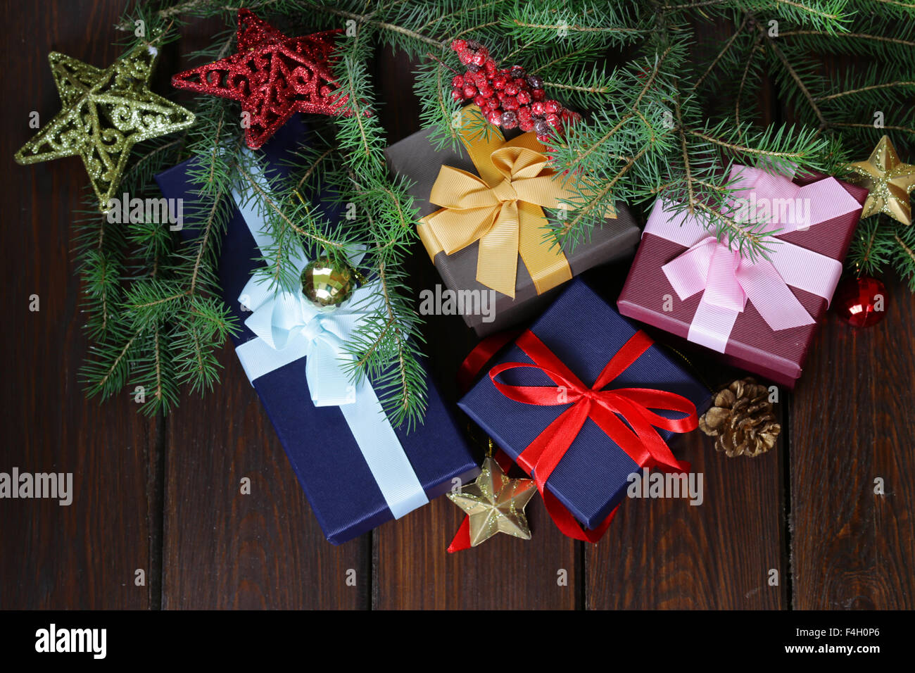 Geschenk-Boxen mit festlichen Bändern und Weihnachtsschmuck auf einem hölzernen Hintergrund Stockfoto