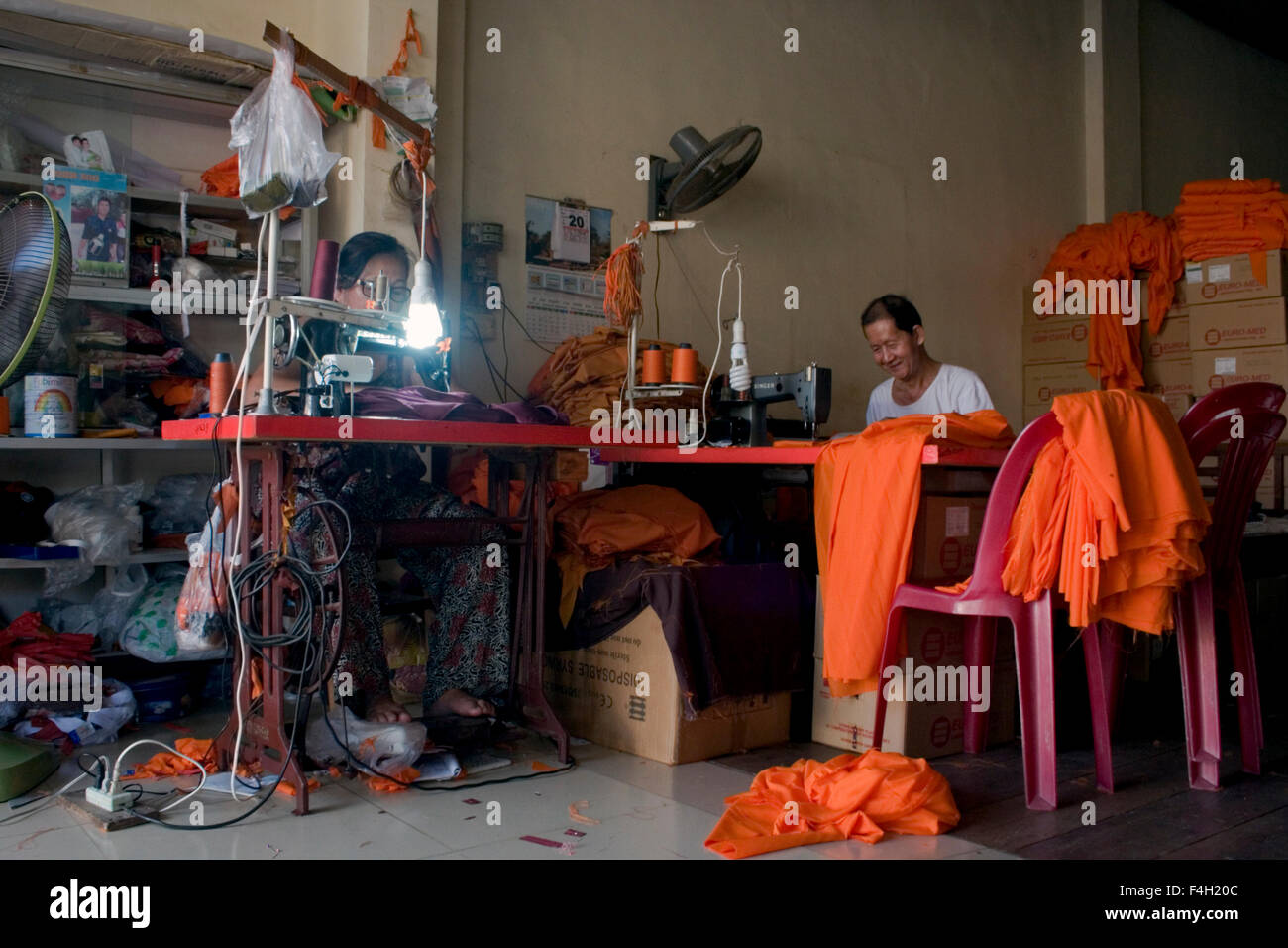 Ein Mann und eine Frau machen Safran Roben für buddhistische Mönche in einem Geschäft in Kampong Cham, Kambodscha. Stockfoto
