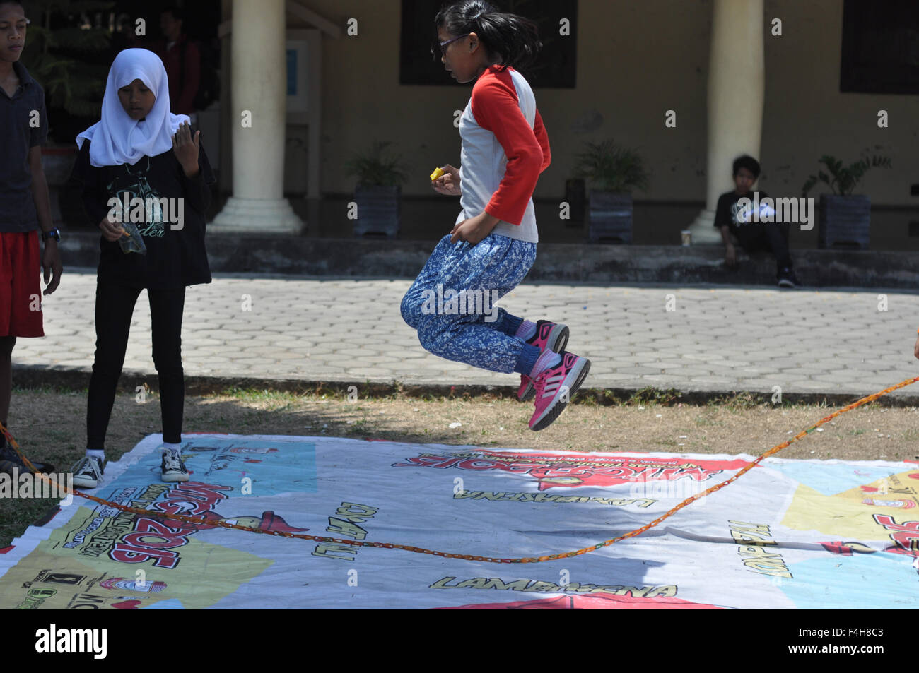 Makassar, Indonesien. 18. Oktober 2015. Eine Mädchen springt über ein Kautschuk-Seil beim traditionellen Games Festival in Makassar, Indonesien am Oktober 18,2015. Dieses Fest fand, Arten der traditionellen Spiele gespielt von Makassar Kids in der Vergangenheit einführen. Viele traditionelle Spiele in Indonesien wurden verschwunden in dieser modernen Welt aufgrund der Weiterentwicklung der Technologie, die viele Spiele durch Handys und Videospielen bieten. Die meisten indonesischen traditionelle Spiele sind physische Spiele, die Kind Psychomotorik lernen verbessern können. Bildnachweis: Yermia Riezky Santiago/Alamy Live-Nachrichten Stockfoto