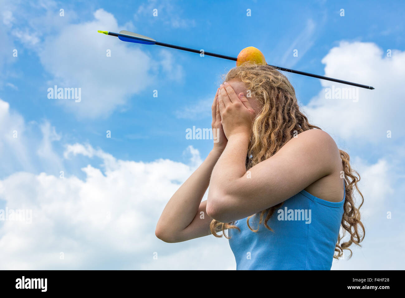 Teenager-Mädchen über ihr Gesicht Gefühl Angst mit Apfel und Pfeil auf Kopf Stockfoto