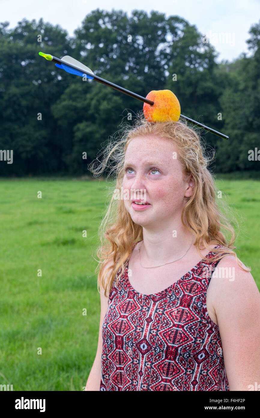 Junge Frau, die Angst bei Arrow in Apple auf Kopf im freien Stockfoto