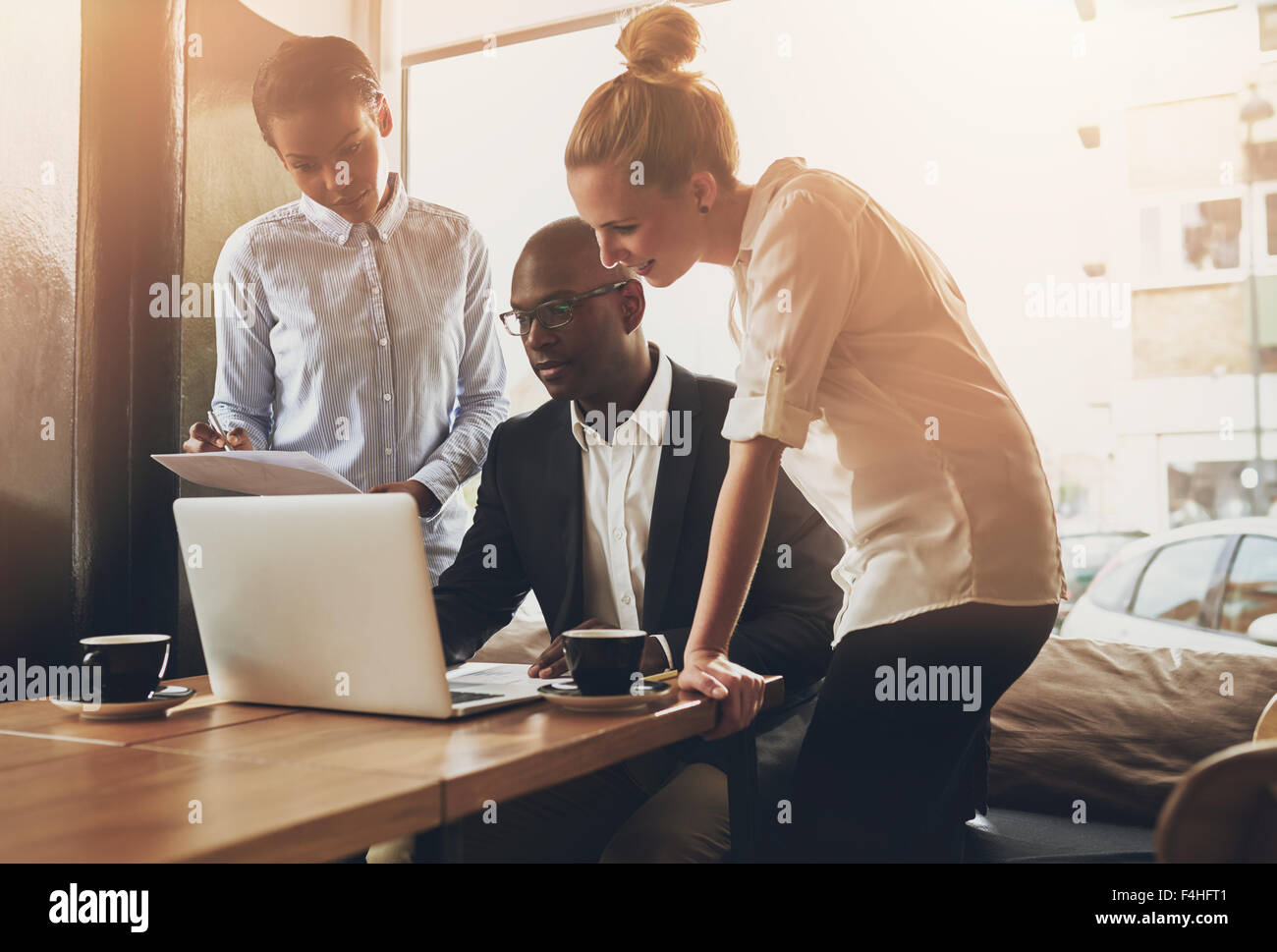Gruppe von Unternehmern, die Arbeiten mit einem Laptop und halten ein Dokument Stockfoto
