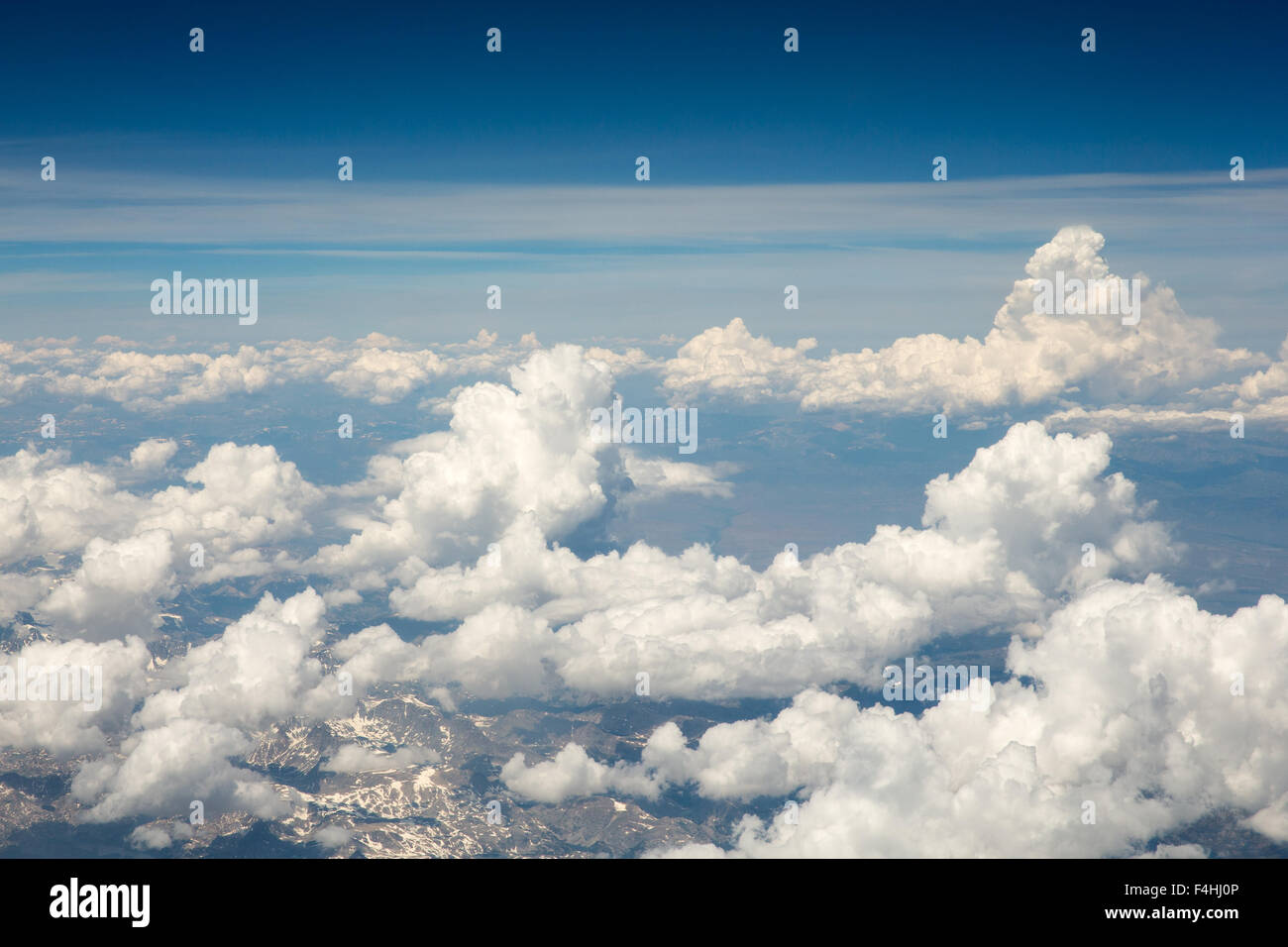 Flauschige weiße Wolken aus dem Flugzeug betrachtet.  Schneebedeckten Rocky Mountains kann durch die Wolken zu sehen.  Kopieren Sie Raum. Stockfoto