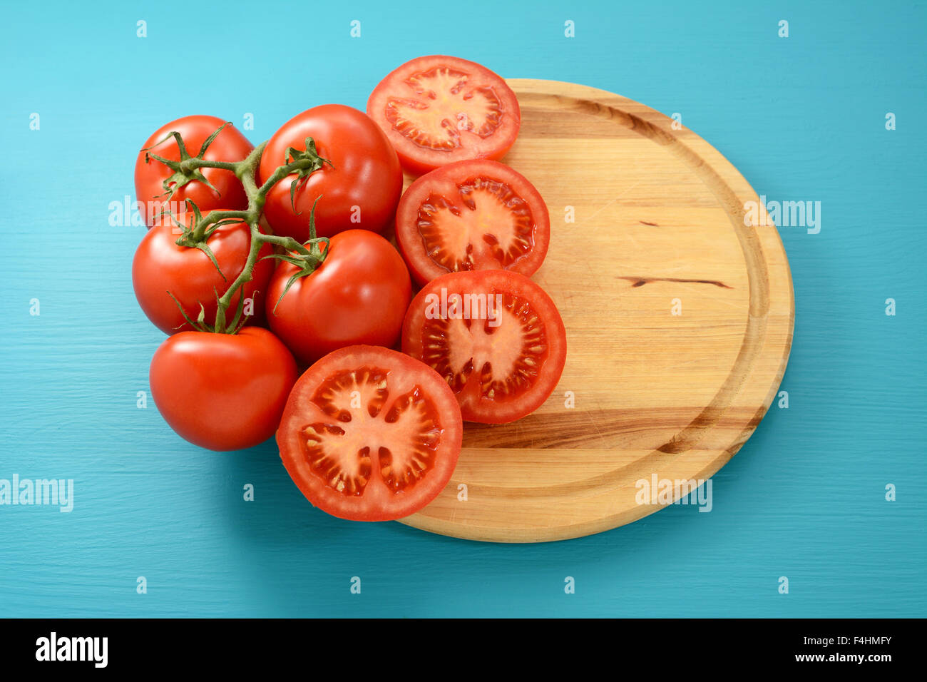 Rotwein-Tomaten ganze und halbierte auf einem runden Holzbrett mit Textfreiraum Stockfoto