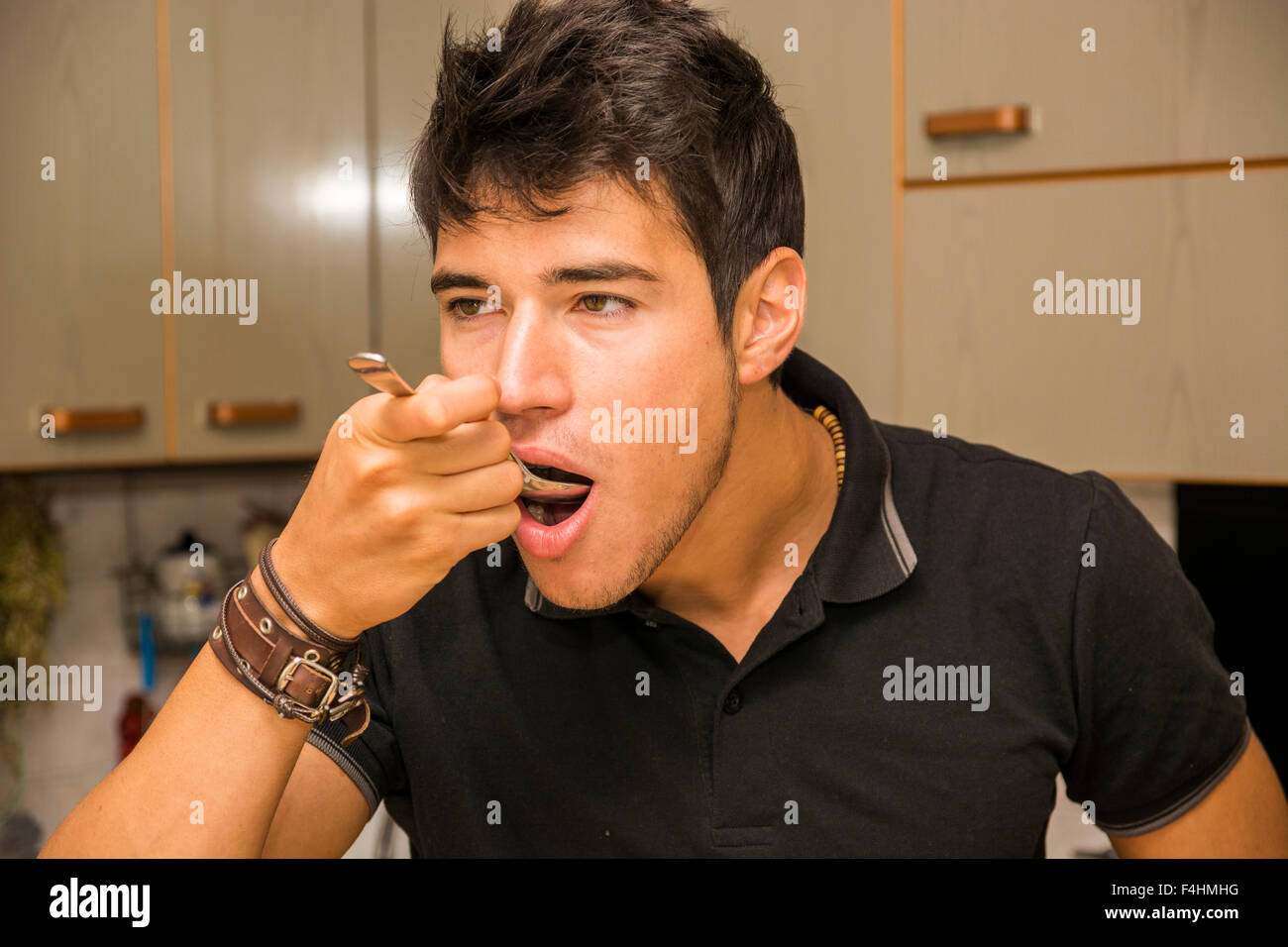 Krank hübscher junger Mann unter Hustensaft oder Medikamente aus Löffel, in der Küche zu Hause Stockfoto