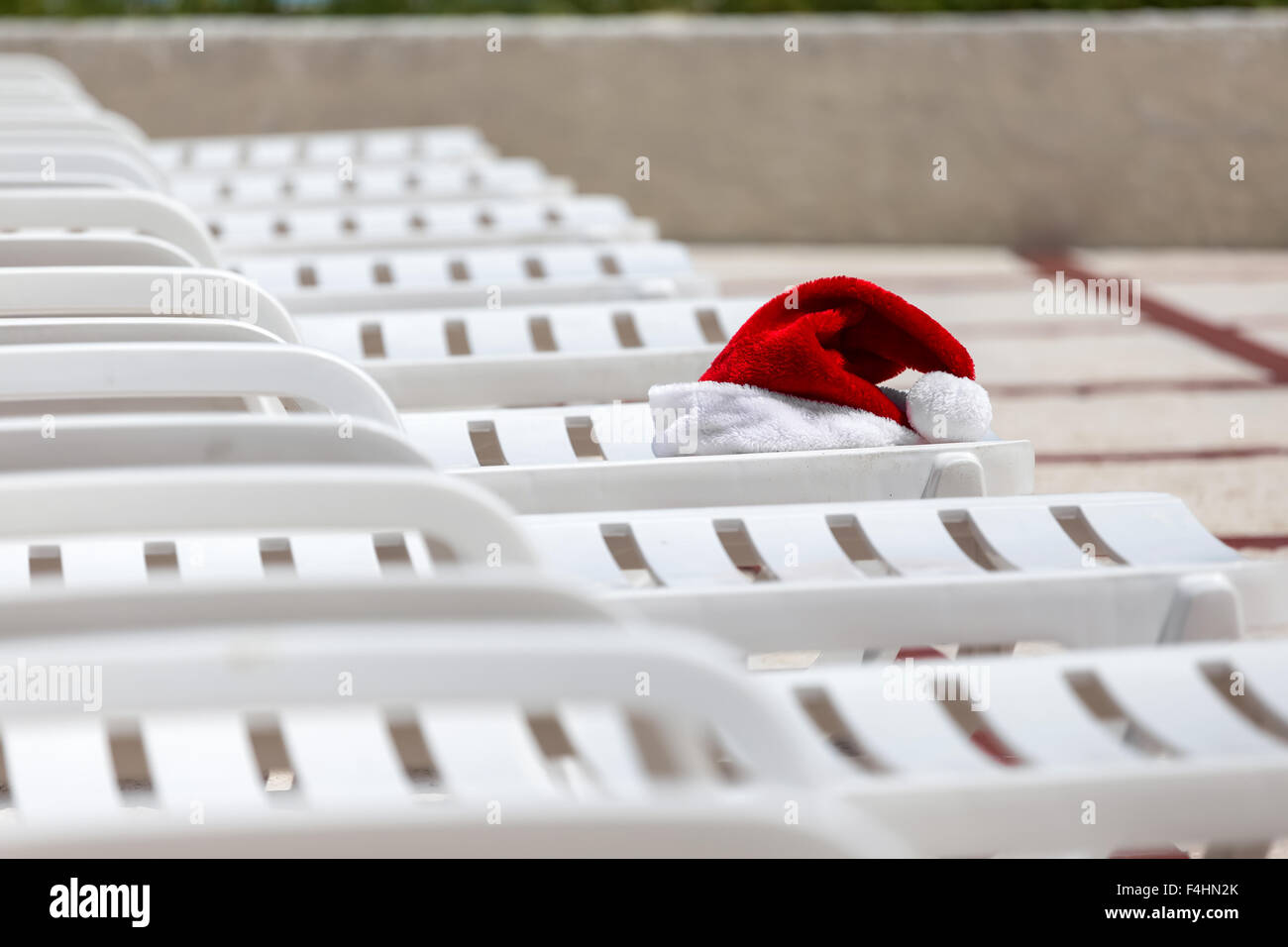 Weihnachtsmann Mütze auf Liegestuhl in der Nähe von Schwimmbad. Weihnachten Urlaub Konzept Stockfoto