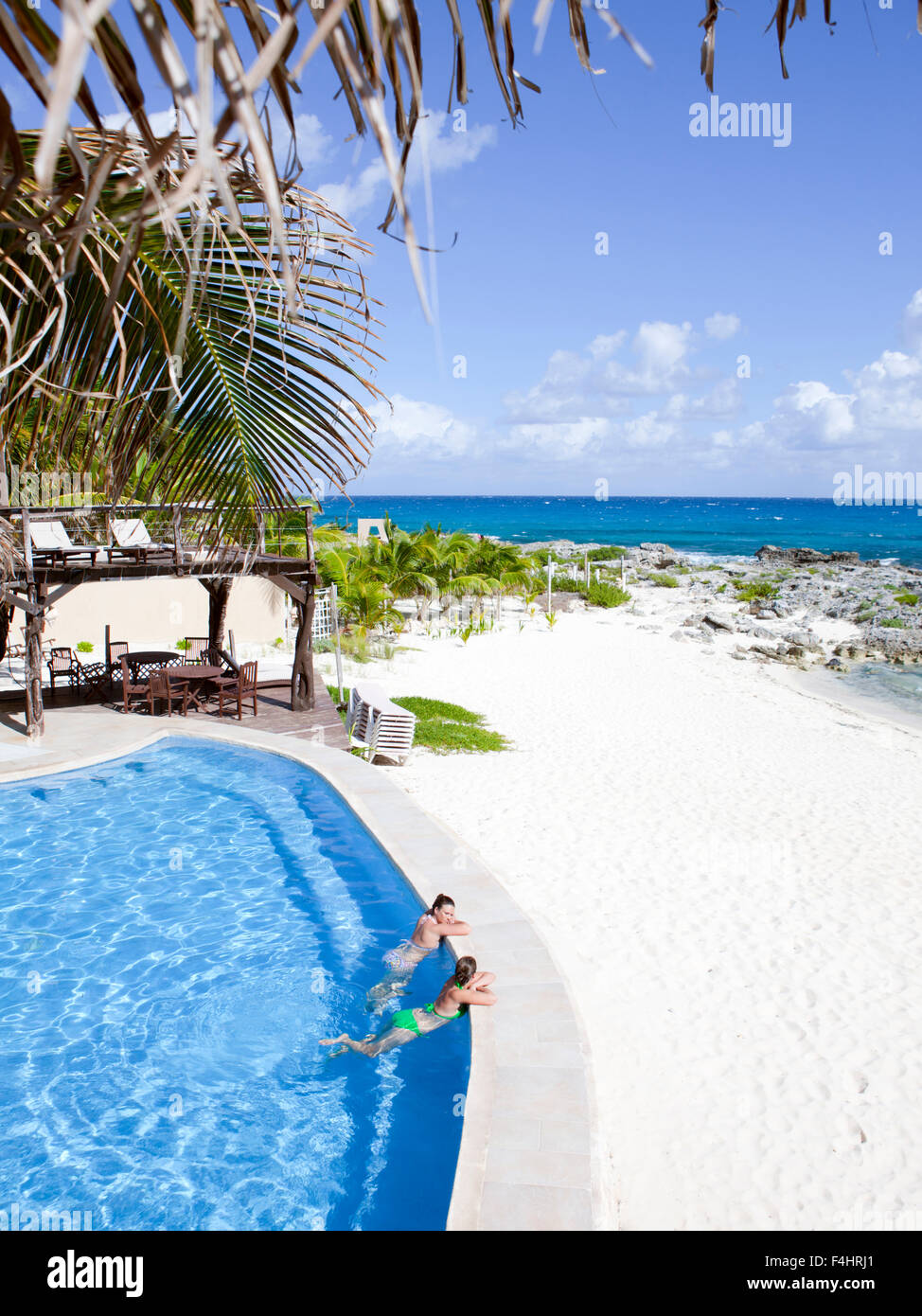 Frauen blicken auf den Ozean von der Infinity-Pool im Hotel Playa la Media Luna, Isla Mujeres, Quintana Roo, Mexiko. Stockfoto