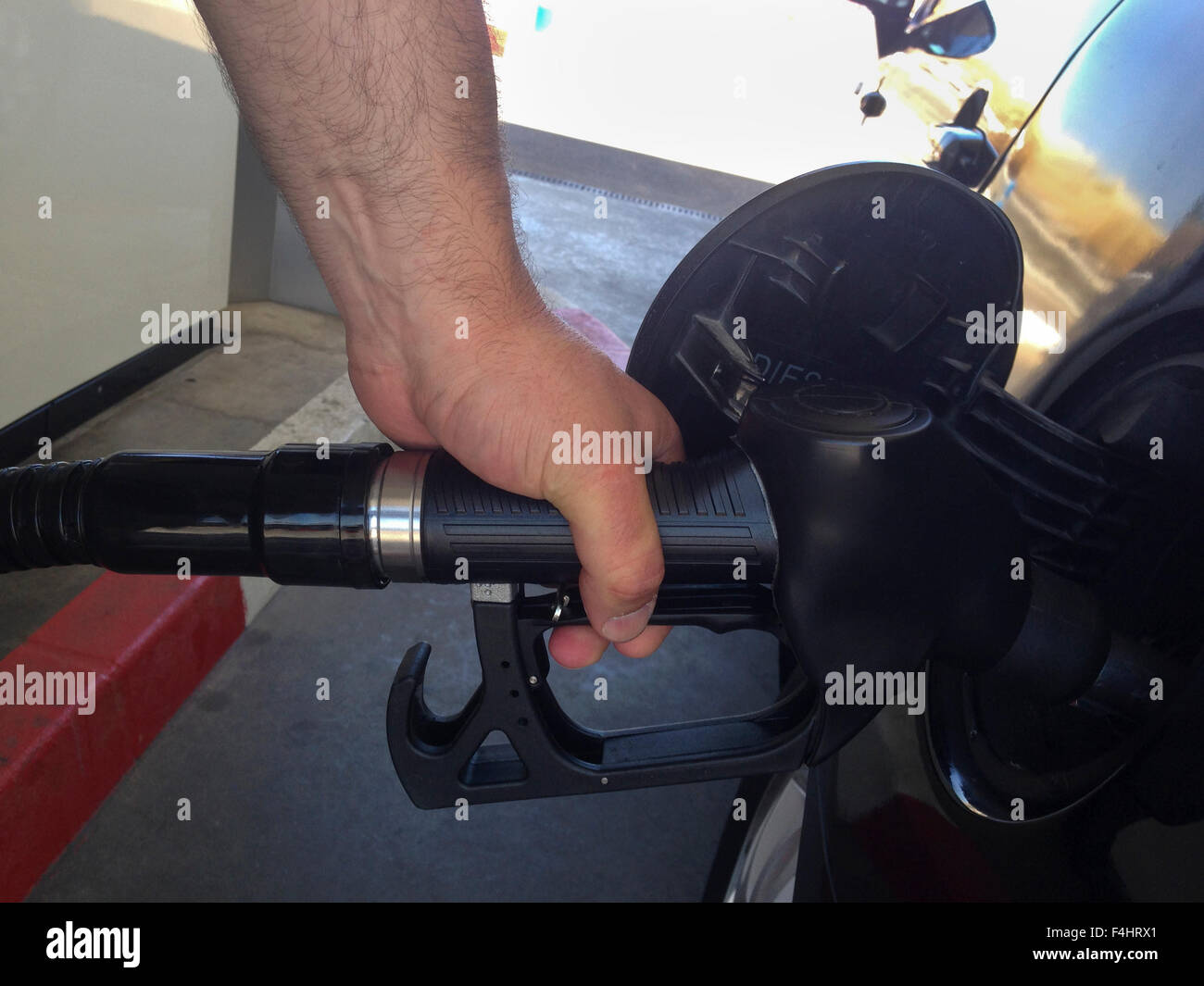 A mans Hand füllt Benzin auf ein schwarzes Auto Stockfoto