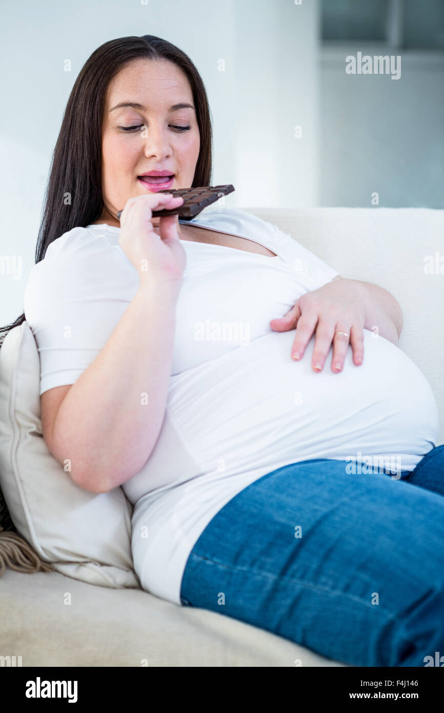 Lächelnde schwangere Frau Schokolade essen Stockfoto