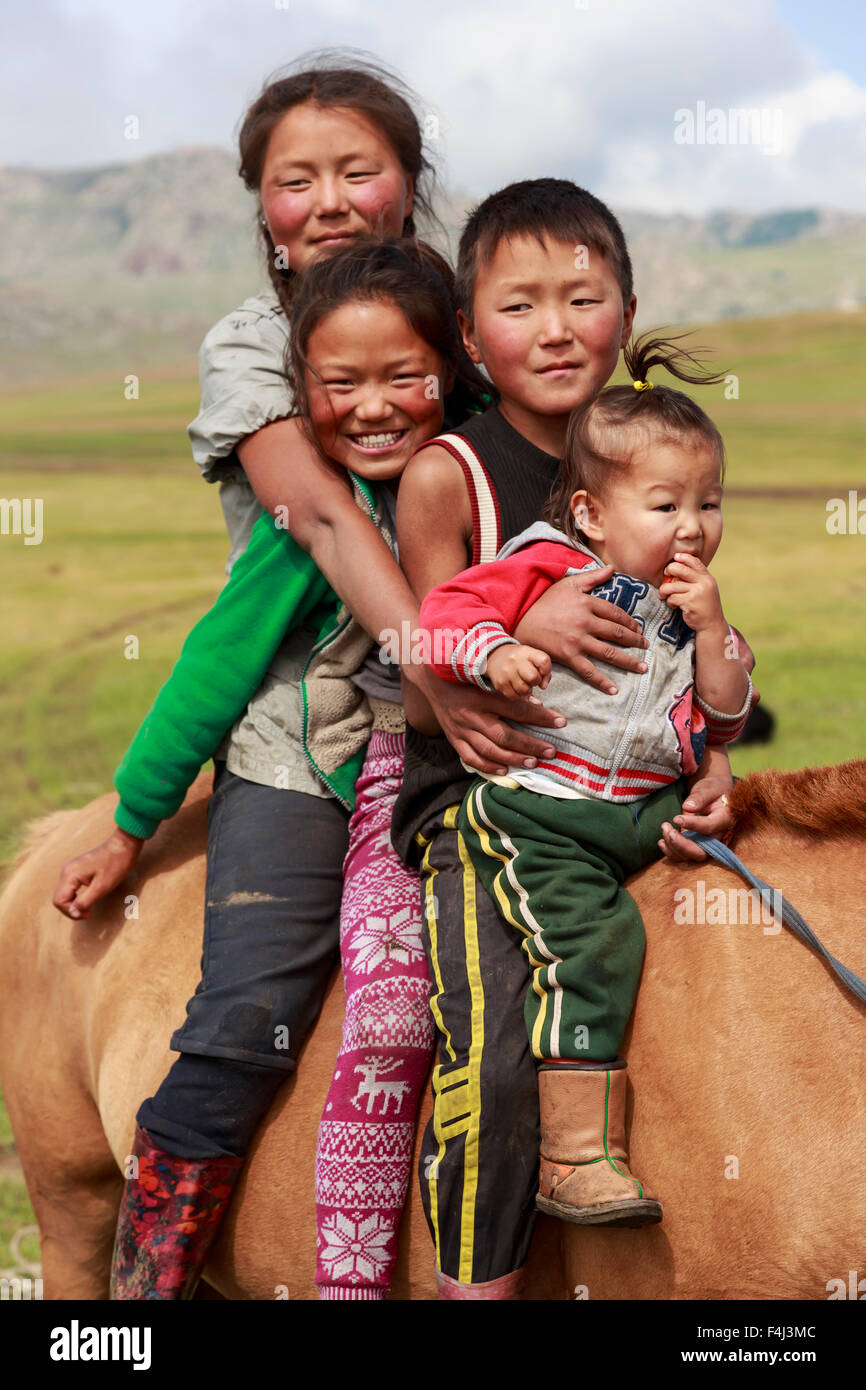 Porträt von vier lächelnd und glücklich Nomad Geschwistern auf ihre zahmen Pferde im Sommer Nomadencamp, Khujirt, Uvurkhangai, Mongolei Stockfoto