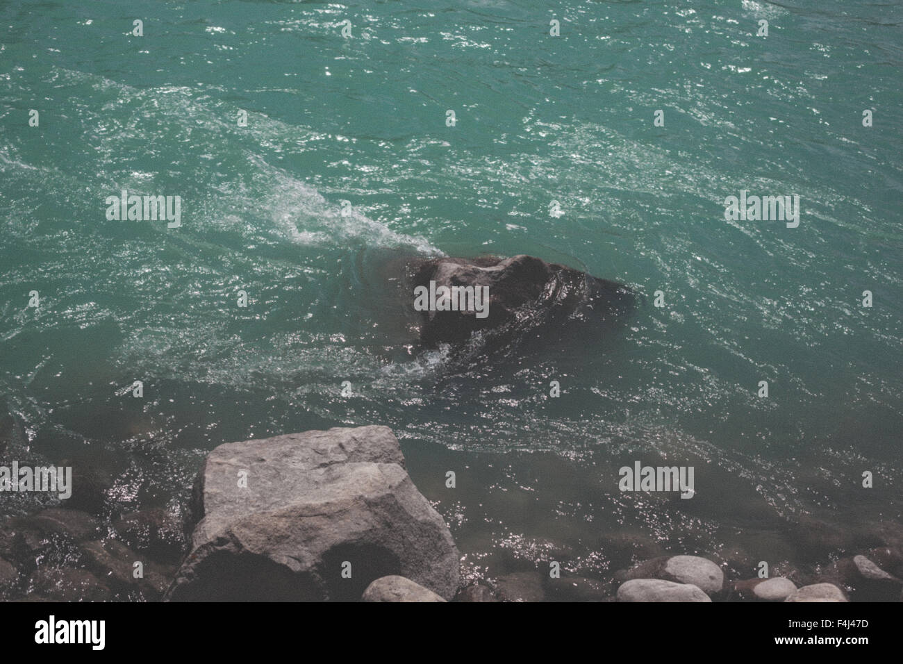 Türkisfarbene Wasser läuft über die Felsen Stockfoto