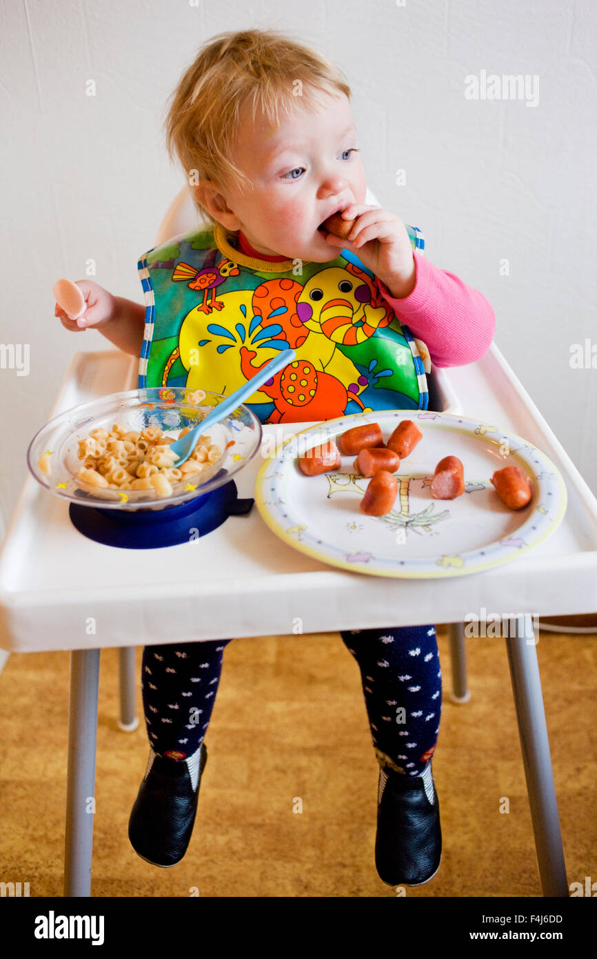 Mädchen sitzen in einem Hochstuhl Essen, Schweden. Stockfoto