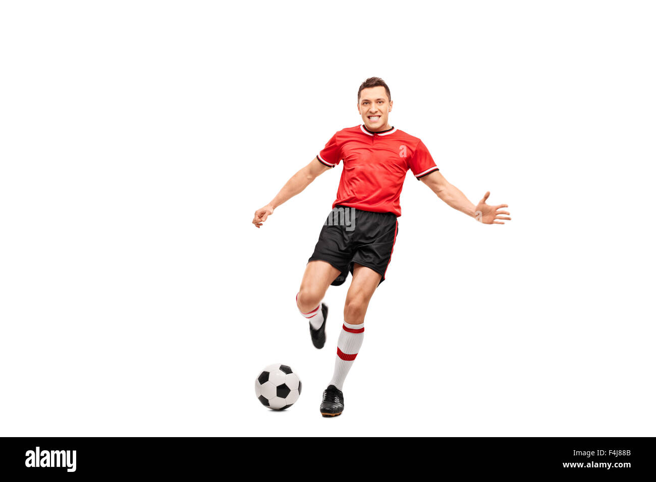 In voller Länge Portrait eines entschlossenen jungen Fußballspielers schießen einen Ball und schaut in die Kamera Stockfoto