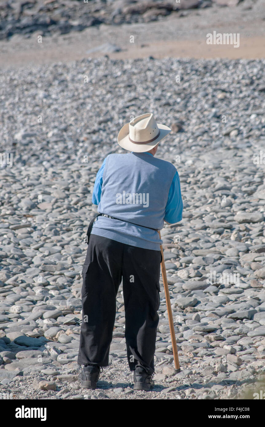 Ein Mann hält einen Spazierstock, Blick auf einen Strand in Cornwall Stockfoto