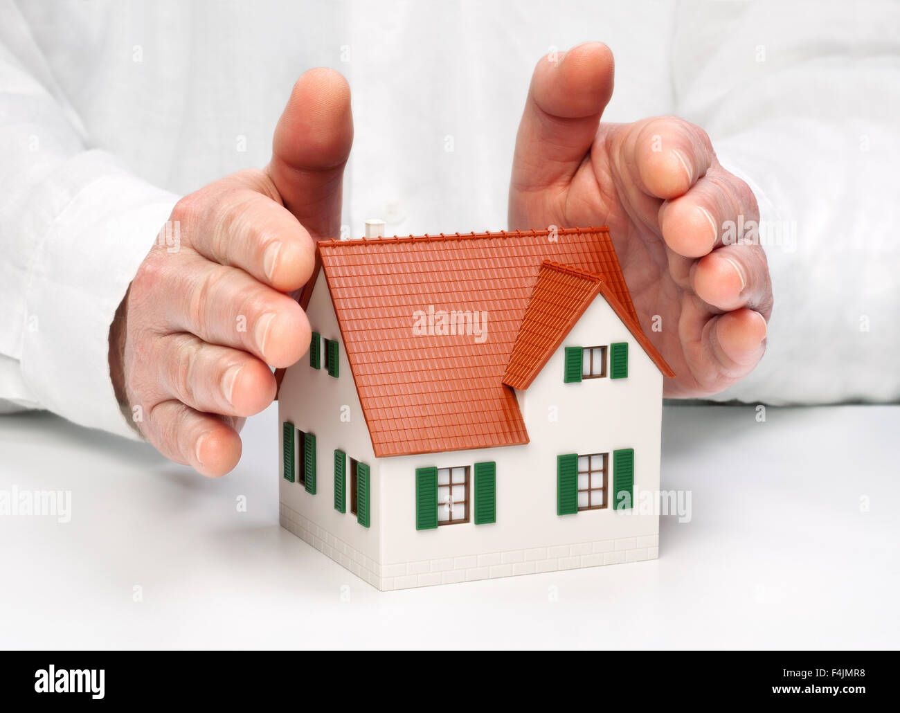Händen umschließen schützend ein Haus. Stockfoto