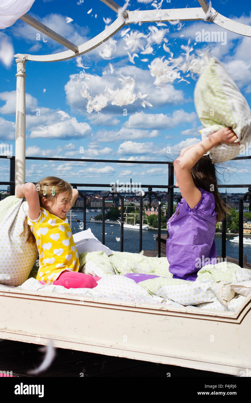 Zwei Mädchen, die Beteiligung an Kissen kämpfen auf Balkon Stockfoto