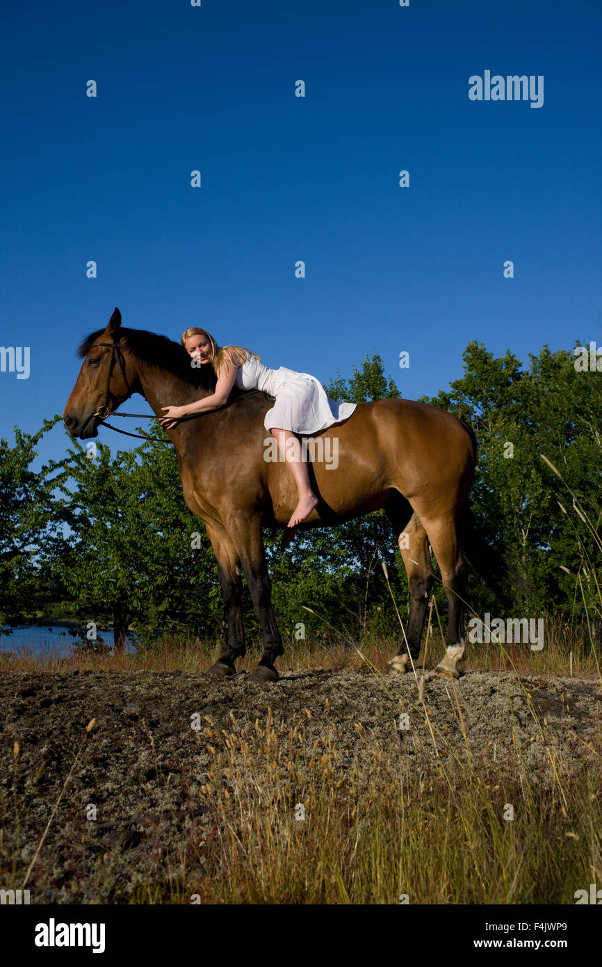 Frau liegend auf Pferd Stockfoto