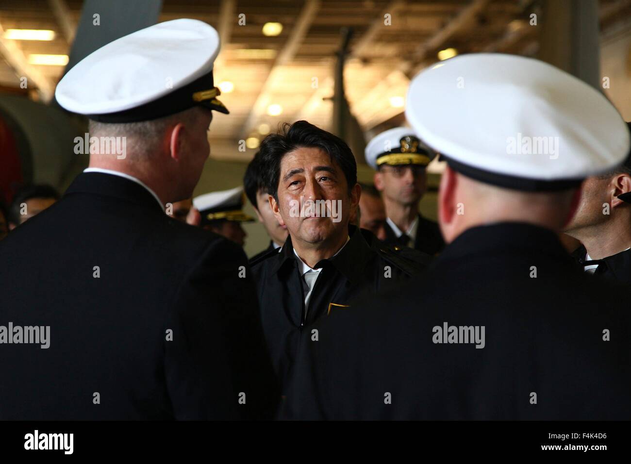 Der japanische Premierminister Shinzo Abe, Center, Plays als Captain Christopher Bolt, links, von der US Navy Nimitz-Klasse nuklearen Flugzeugträger USS Ronald Reagan erklären Betriebsabläufe an Bord bei einem Rundgang durch die Hangarbucht 18. Oktober 2015 in der Bucht von Tokio, Japan. Stockfoto