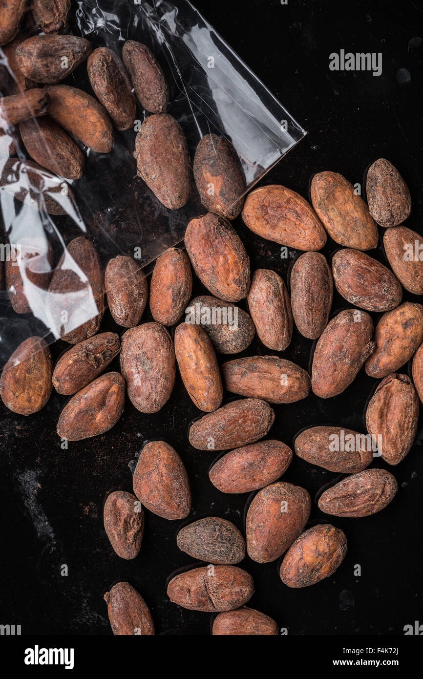 Geröstete Kakaobohnen aus einem Zellophan Beutel verschütten Stockfoto