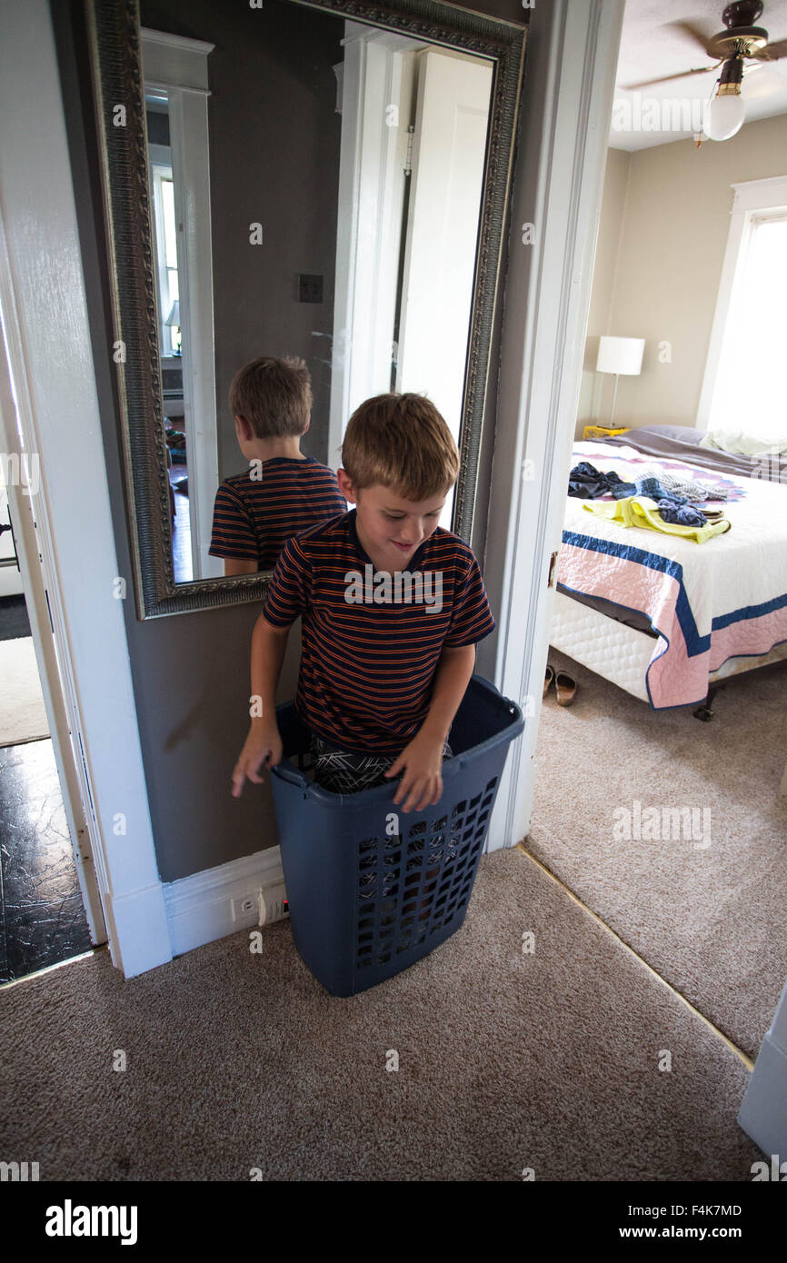 Kleiner Junge spielt und steht in seiner Heimat Flur in einen Wäschekorb Stockfoto