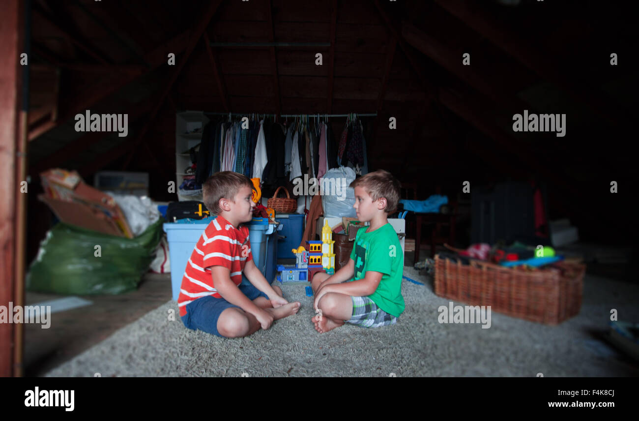 Zwei männliche Zwillinge spielen miteinander in ihrer Familie Dachboden Stockfoto