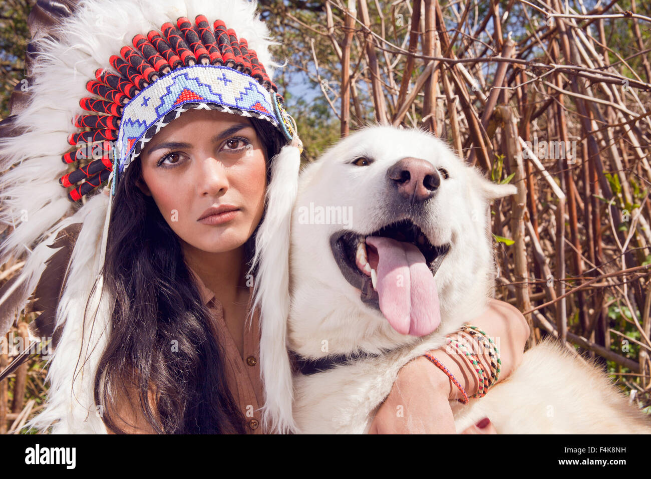 Sadia Khaliq gekleidet in indianischen indische Stammes-Kleidung eine Squaw mit einer Feder Haube mit ihrem Husky dog.a UK Stockfoto