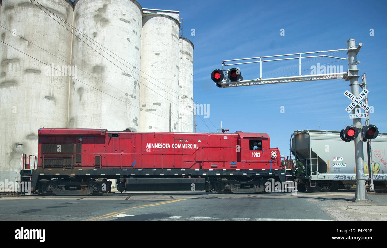 Eisenbahn-Motor Zug über die Fahrbahn mit veralteten Getreidesilos im Hintergrund ziehen. Minneapolis Minnesota MN USA Stockfoto
