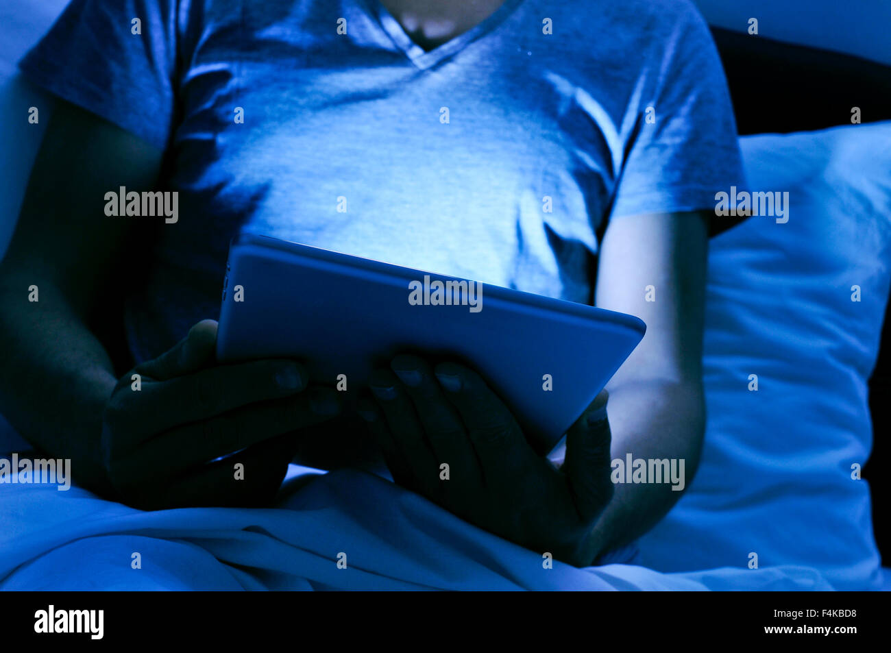 Nahaufnahme eines jungen Mannes mit einem Tablet im Bett in der Nacht Stockfoto