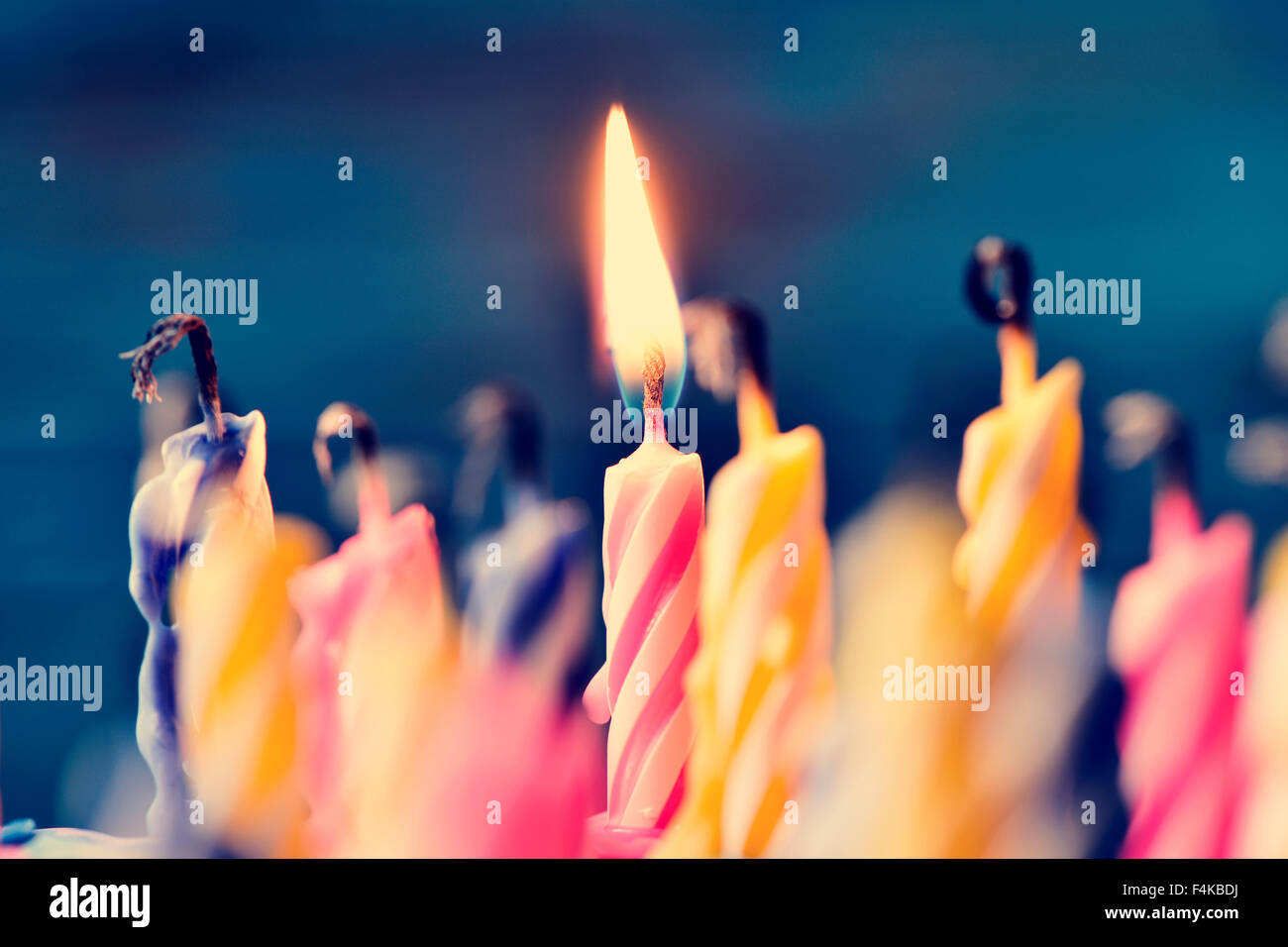 Nahaufnahme von einigen unbeleuchtet Kerzen und nur eine brennende Kerze nach dem Kuchen Ausblasen Stockfoto