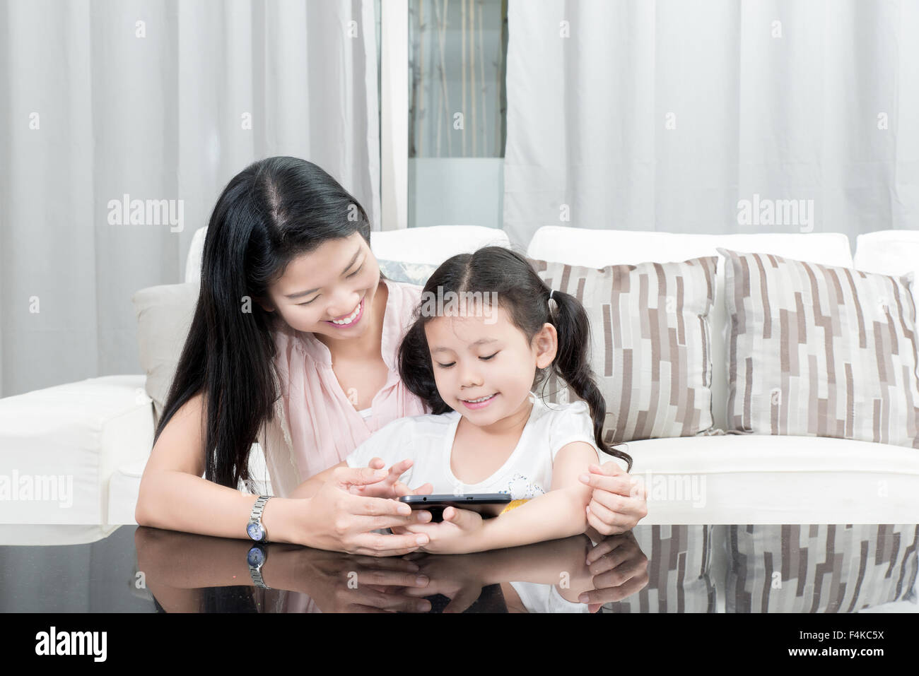Familie, Kinder und glückliche Menschen Konzept - asiatische Mutter und Tochter spielen mit digitalen Tablet zu Hause Stockfoto