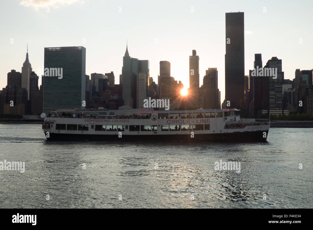 Circle Line Tourenboot geht durch die New Yorker Skyline bei Sonnenuntergang - Blick von Long Island City entfernt, Königin Foto von Jen Lombardo Stockfoto