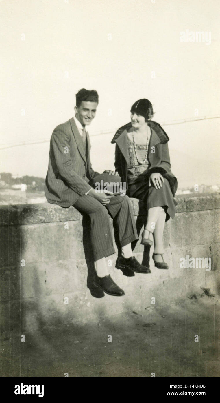 Junges Paar sitzt auf einer Mauer, Italien Stockfoto