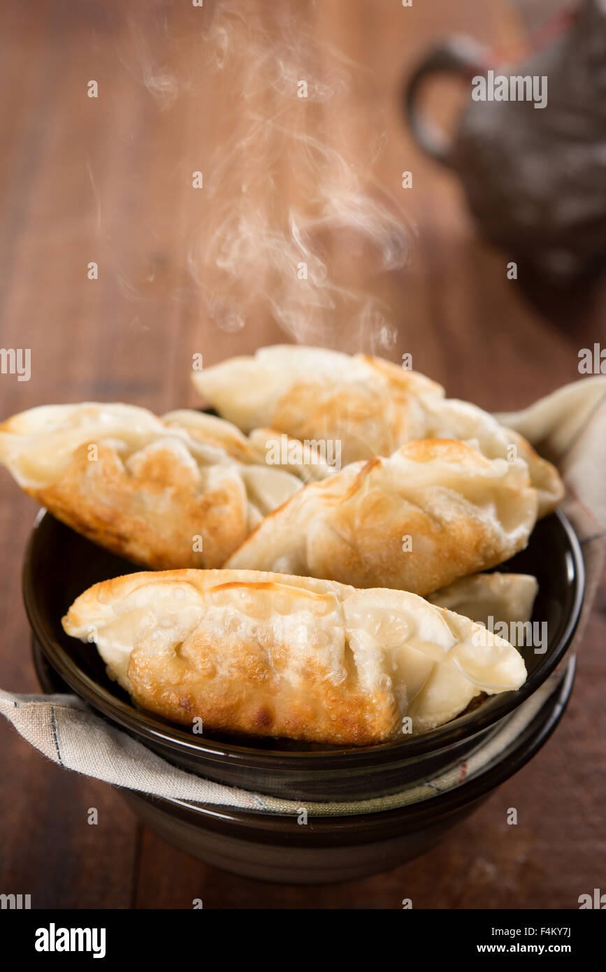 Frische Pfanne Gebratene Knödel auf Schüssel. Chinesisches Gericht mit heißen Dämpfe auf rustikale Vintage Holz-Hintergrund. Stockfoto