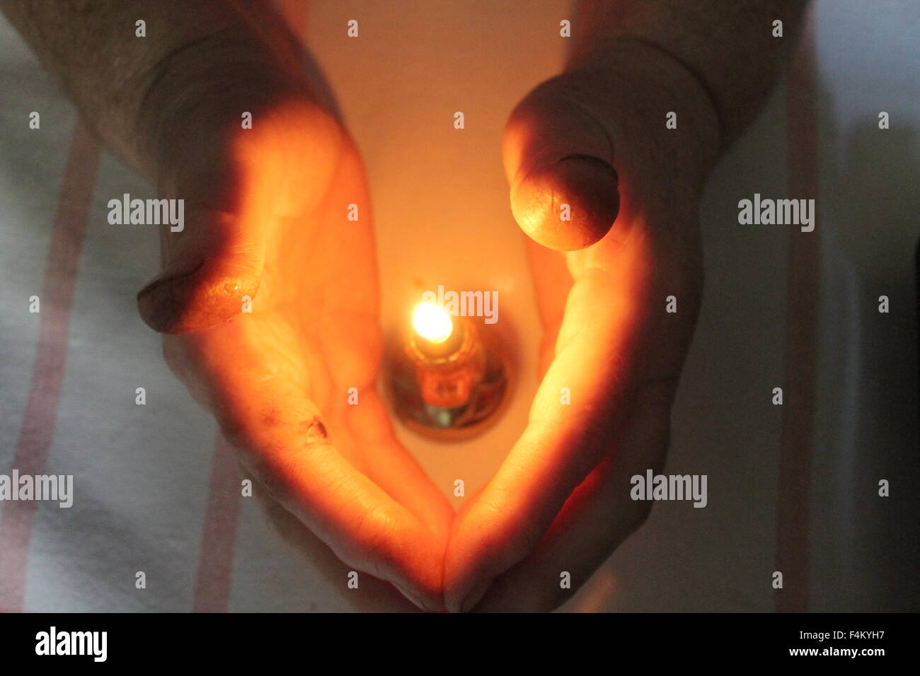 zwei menschliche Palmen umarmen kleine helle Flamme der Kerze Stockfoto