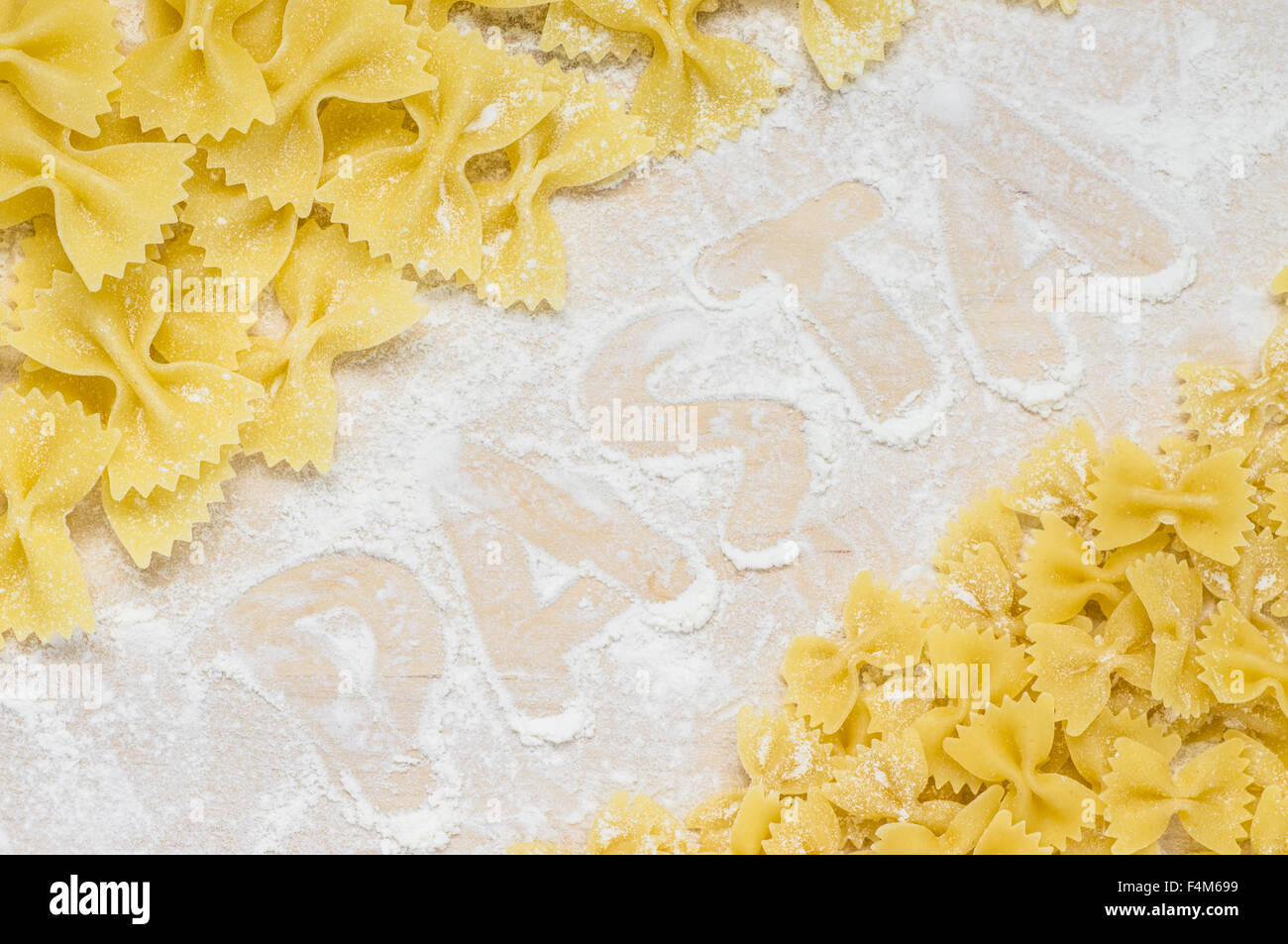 Inschrift auf dem Mehl Wort Pasta auf dem Brett mit Farfalle-Nudeln Stockfoto