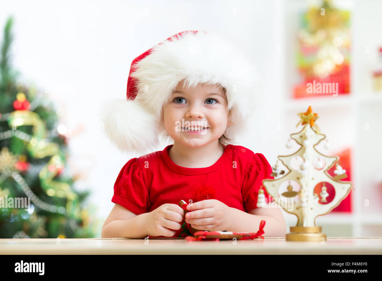 Kleine Mädchen tragen eine festliche rote Weihnachtsmütze mit Weihnachtsgebäck Stockfoto