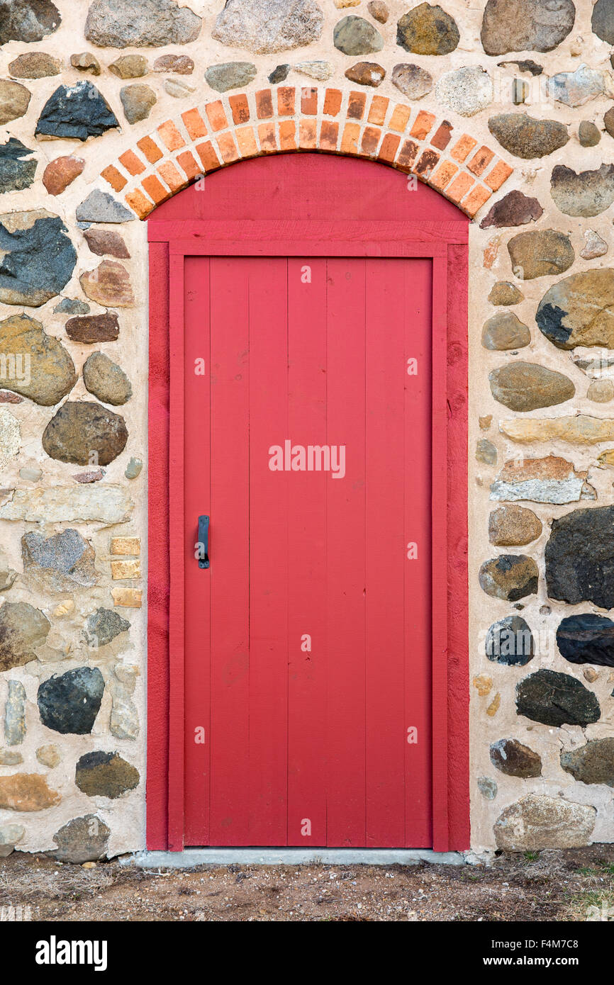 Leuchtend rot gewölbte Tür-Set in einem alten Steinmauer.  Viel Textur und Farbe. Stockfoto