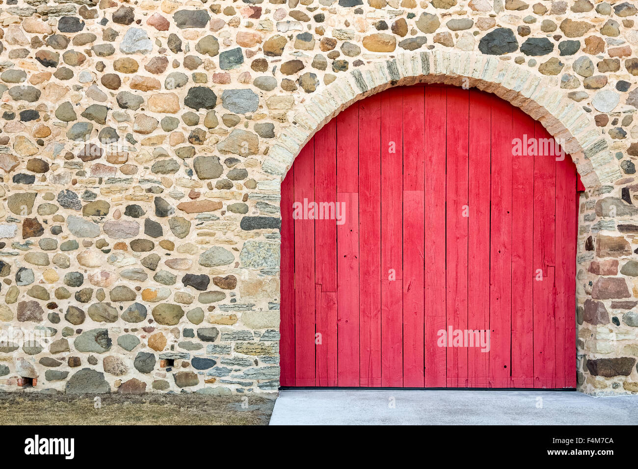 Leuchtend rot gewölbte Tür-Set in einem alten Steinmauer.  Viel Textur, Farbe und Handwerkskunst. Stockfoto