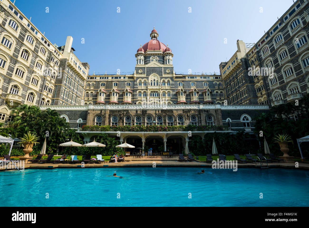 Das Schwimmbad im Inneren des colaba taj mahal palace hotel Courtyard ist mit blauen Wasser gefüllt, die Fassade des Hotels widerspiegelt Stockfoto