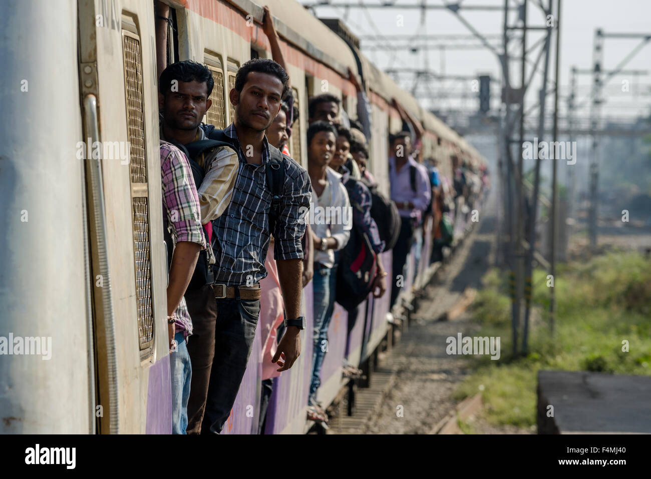 Ein überfüllter gelbe Zug am Bahnhof Churchgate ankommen ist, einige Menschen sind gefährlich Reisen mit lehnte sich aus dem d Stockfoto