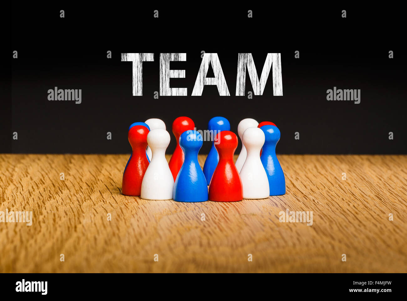 Konzept für Team, Teamarbeit mit weißer Kreide Text. Rote weiße blaue Bauer Figuren und schwarzem Hintergrund auf Eiche. Stockfoto