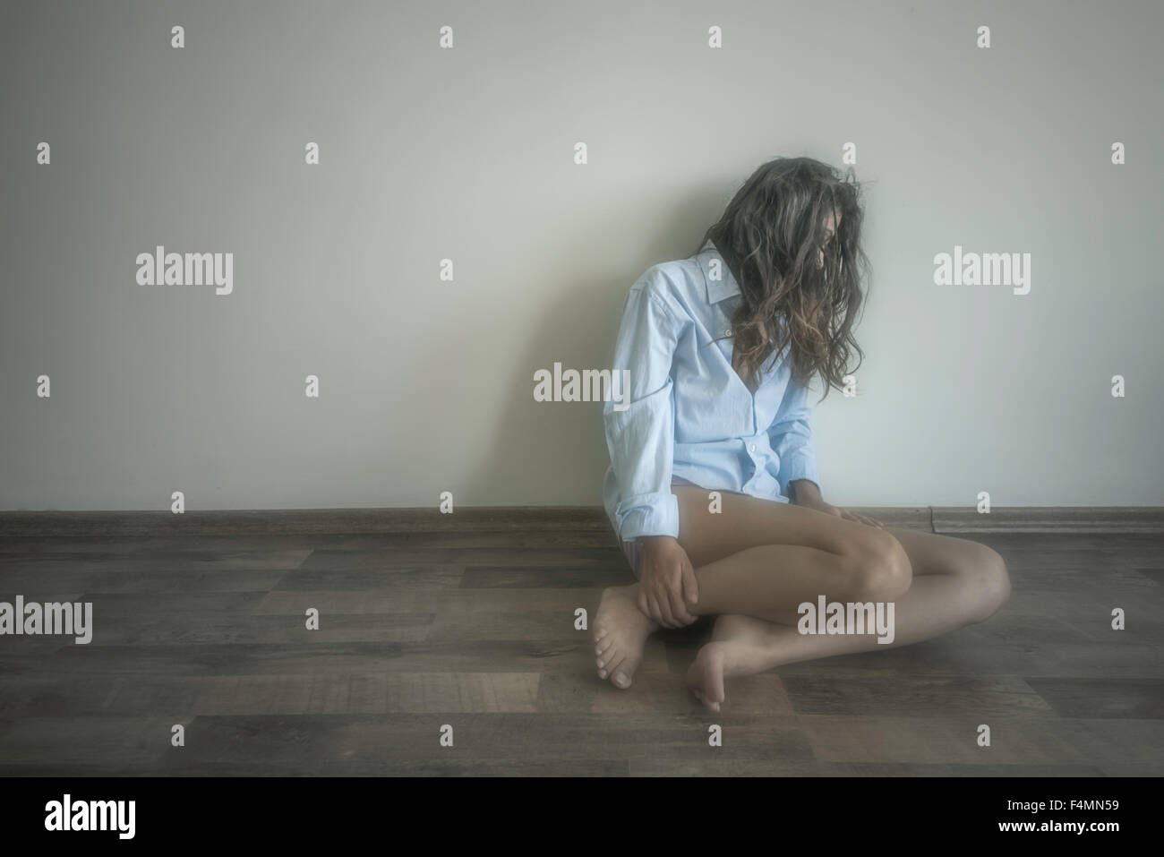 traurige Frau sitzt alleine in einem leeren Raum Stockfoto
